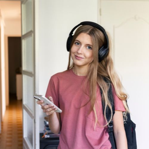 A Teen Girl With Headphones And A Backpack