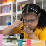 Autistic, Autism or Down Syndrome children girl are painting their own hands