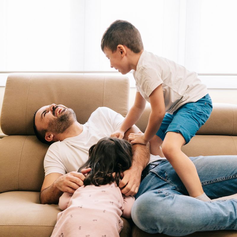Father Plays with His Children on the Couch Father Plays with His Children on the Couch